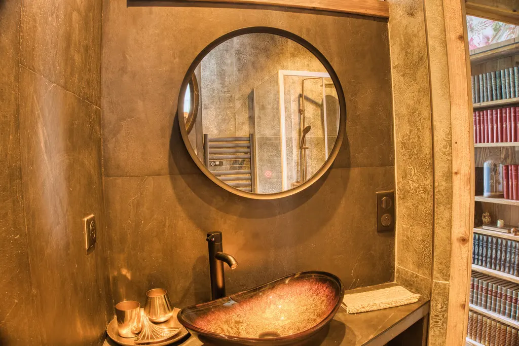 Salle d’eau en béton ciré, vasque en cuivre martelé et miroir rond