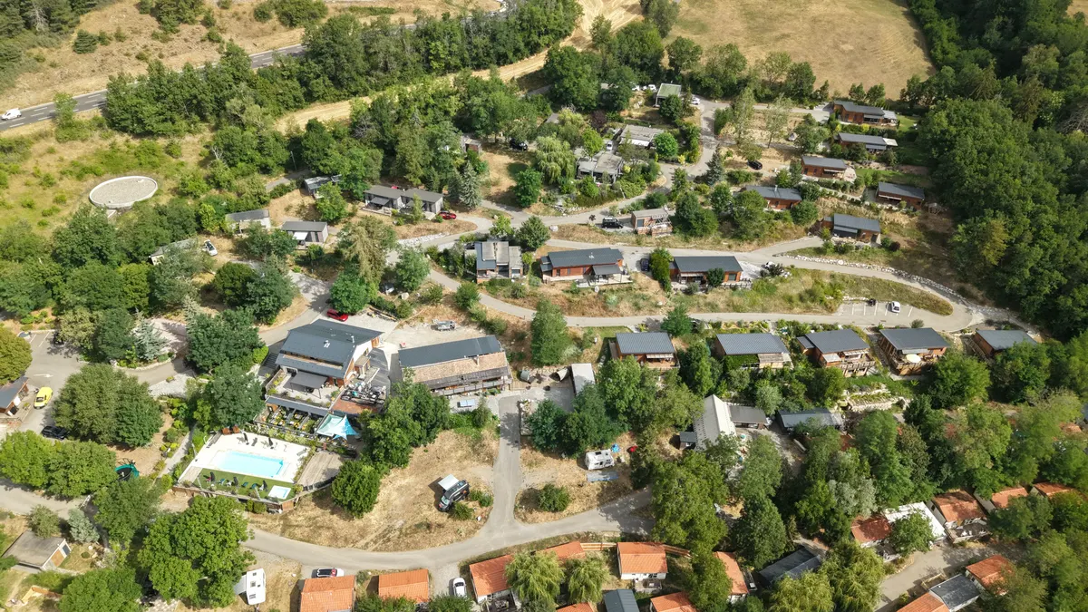 Vue aérienne du camping Le Napoléon à Gap, chalets et piscine au milieu des arbres