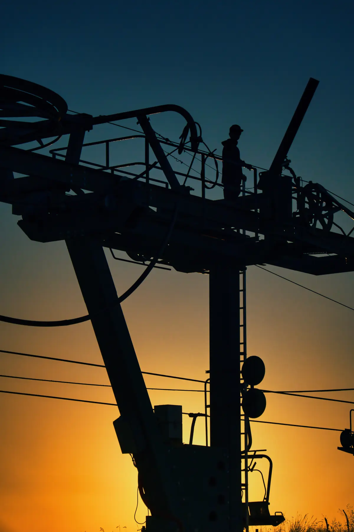 Pylône de télésiège en contre-jour, soleil couchant derrière la structure
